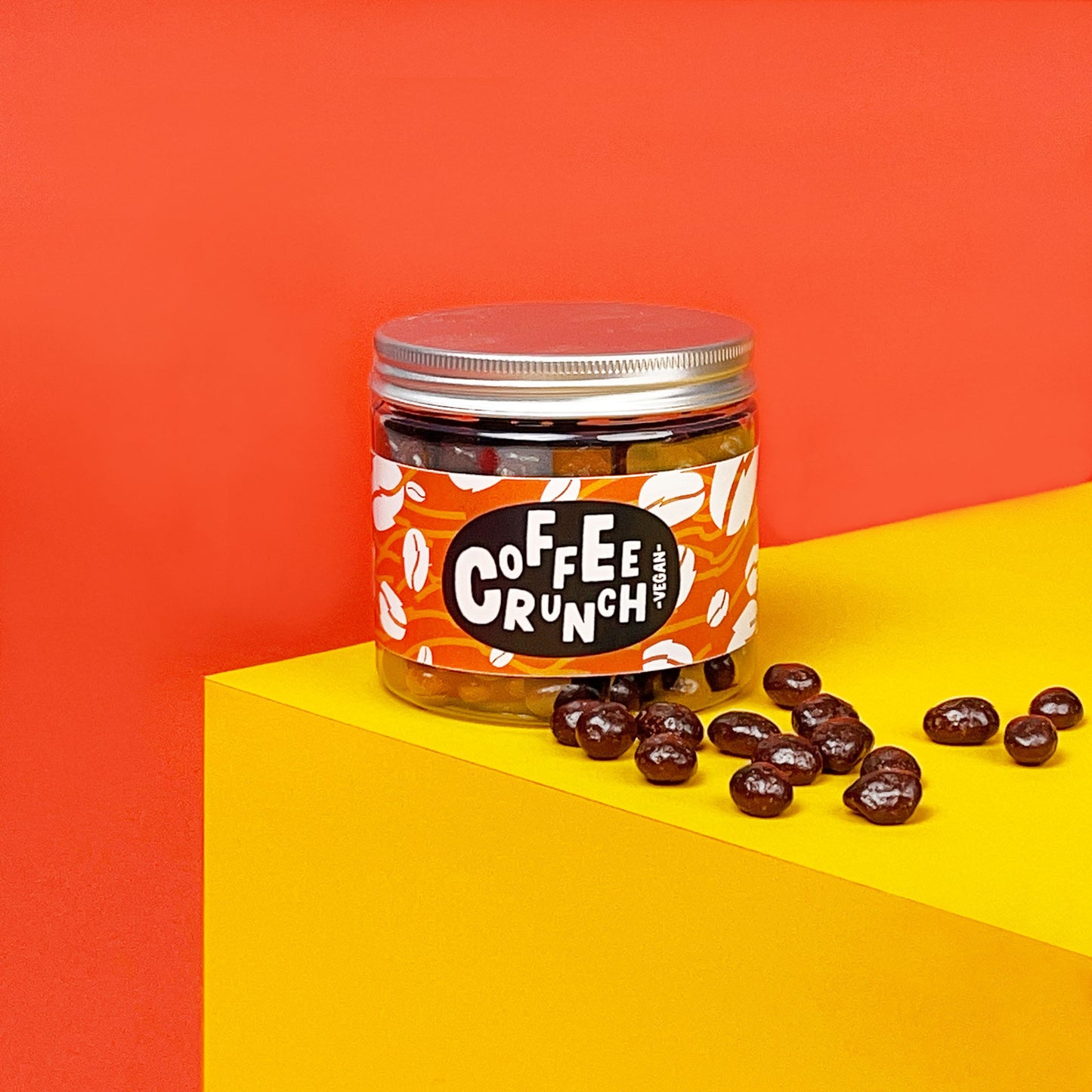 Dose mit schokolierten Kaffeebohnen auf einem bunten Hintergrund. Für den Koffeinkick knuspern sie herrlich am Nachmittag.